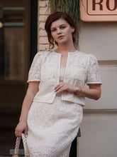 A lady wears a white skirt and a cropped jacket.